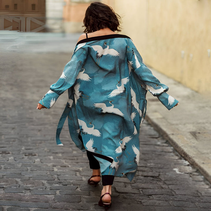 Femme vue de dos portant un kimono bleu imprimé de grues blanches. Vêtement de style japonais pour femme, disponible à l'achat en ligne. Idéal pour un look élégant et décontracté. Boutique de kimonos en ligne.