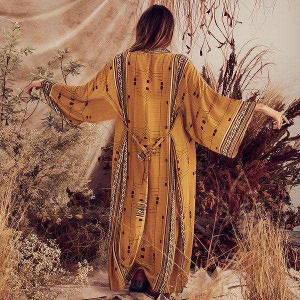 Femme portant un kimono long jaune moutarde avec motifs géométriques. Vêtement de style bohème, parfait pour un look tendance. Kimonos à vendre.