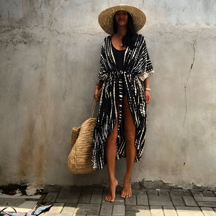 Femme portant un kimono noir et blanc avec un chapeau de paille et un sac en paille, disponible à l'achat. Mode kimono.