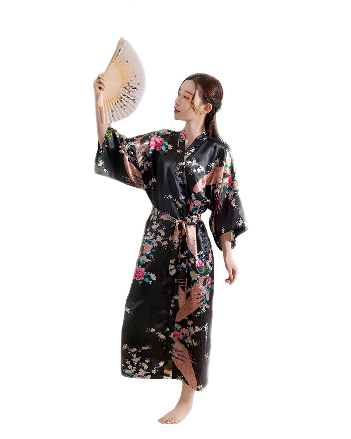 Femme portant un kimono noir à motifs floraux et tenant un éventail. Vêtements japonais traditionnels à vendre. Boutique de kimonos en ligne.