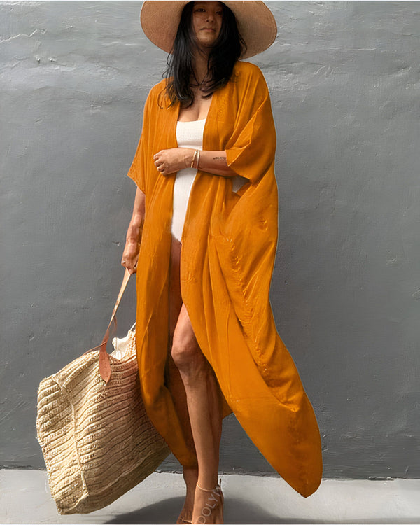 Femme portant un kimono orange, maillot de bain blanc, chapeau de paille et sac de plage. Vente de kimonos élégants et confortables pour toutes les occasions. Découvrez notre collection de kimonos uniques et de qualité.
