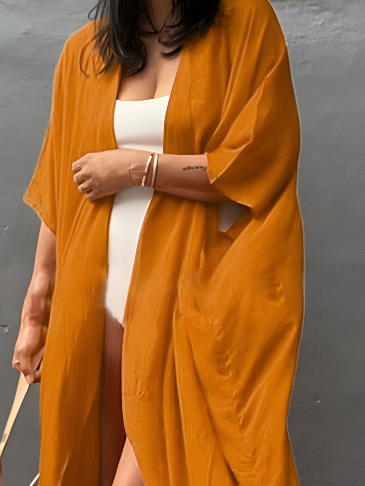 Kimono orange porté par-dessus un maillot de bain blanc, vêtement d'été léger et élégant. Découvrez notre collection de kimonos pour femmes.