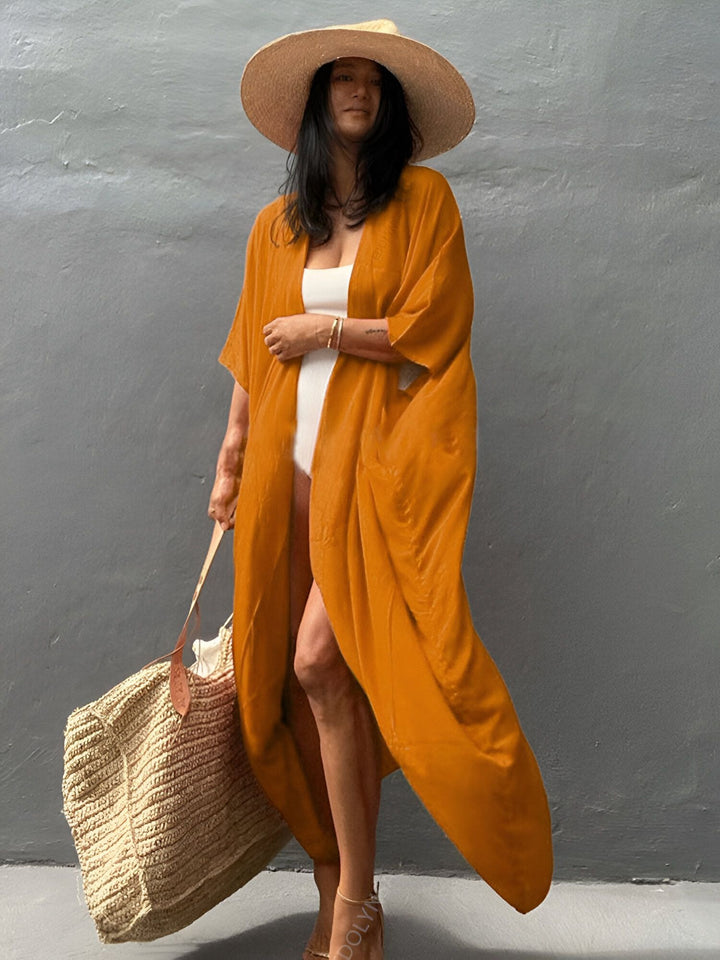Femme portant un kimono orange vif, un maillot de bain blanc et un chapeau de paille. Sac de plage en osier. Mode kimono, vêtements de plage.
