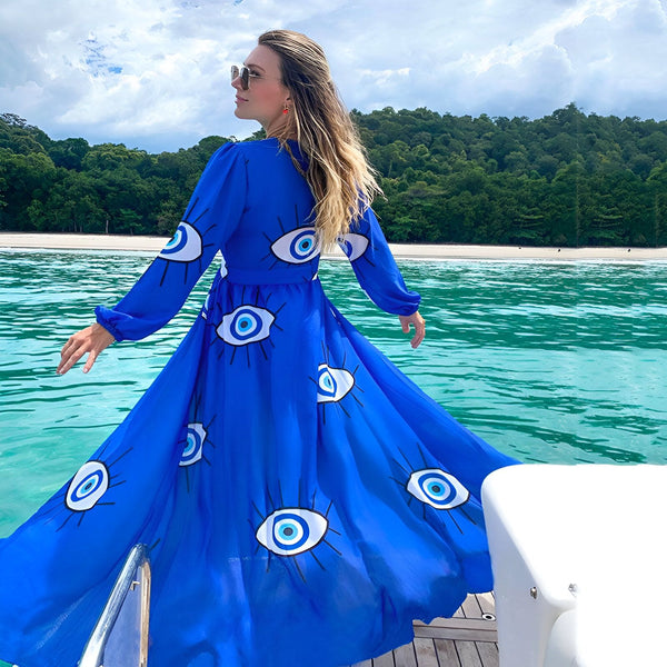 Femme portant un kimono bleu vif à motifs d'yeux sur un bateau. Vue sur l'océan et la forêt tropicale. Kimonos pour femmes, vêtements de plage tendance.