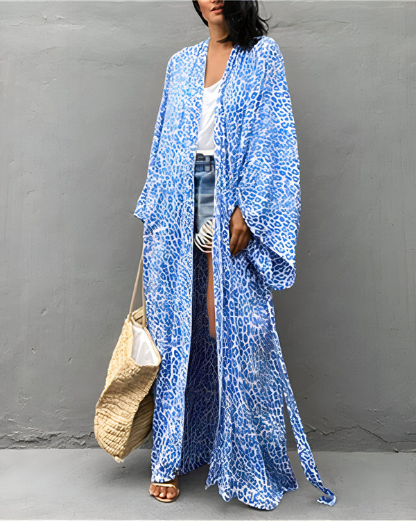 Femme portant un kimono long bleu à imprimé animal, avec un short en jean et un sac en paille. Kimono tendance pour femmes, idéal pour l'été.
