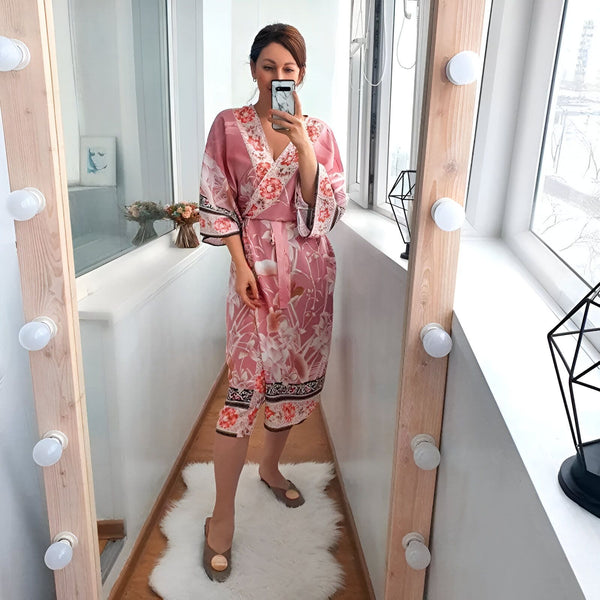 Femme prenant un selfie dans un miroir, portant un kimono rose à motifs floraux. Vente de kimonos en ligne. Mode japonaise.