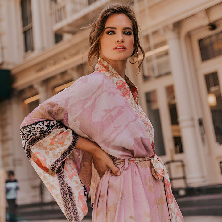 Femme portant un kimono rose à motifs floraux. Kimonos élégants et confortables à découvrir.
