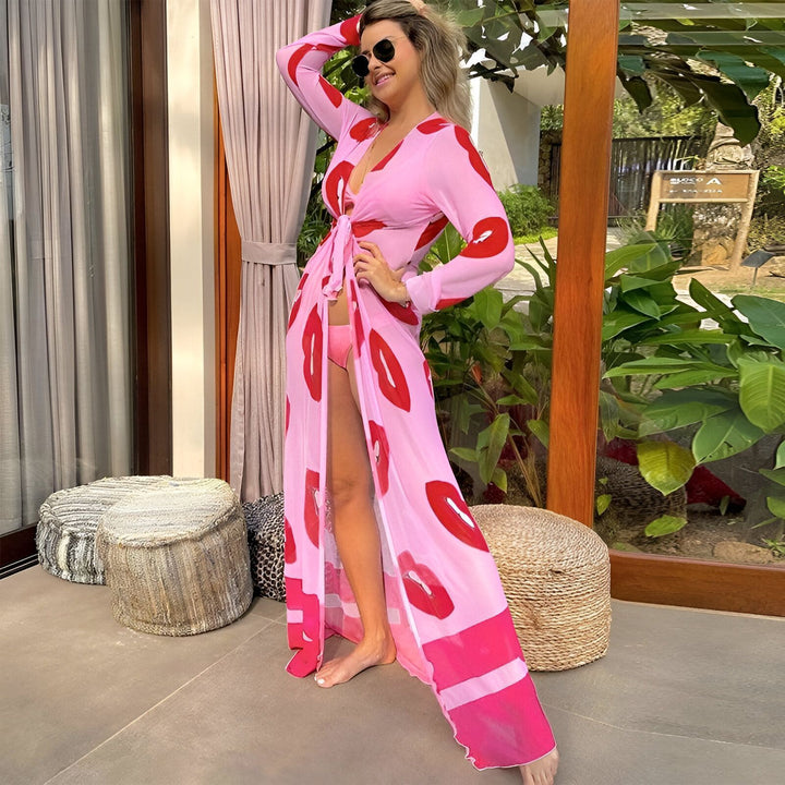 Femme portant un kimono rose imprimé lèvres rouges. Kimono long et léger, parfait pour la plage ou la maison. Mode estivale, vêtement de détente, style unique.