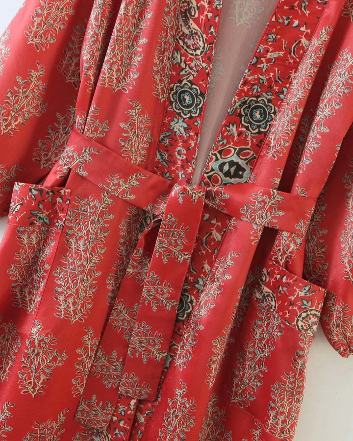 Kimono rouge avec motifs floraux et cachemire. Vêtement d'intérieur élégant et confortable. Détails de poches et ceinture assortie. Parfait pour se détendre avec style. Kimonos en vente.