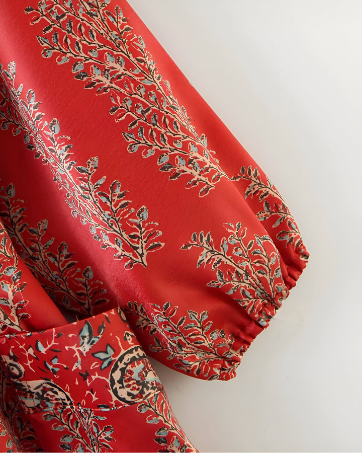Détail d'un kimono rouge avec motifs floraux stylisés. Texture du tissu en gros plan, manches bouffantes. Mode et élégance inspirées du Japon.