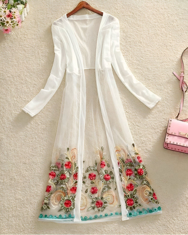 Kimono long blanc transparent avec broderies florales colorées, présenté sur un cintre. Vêtement d'été léger et élégant.