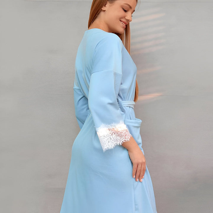 Femme portant un kimono bleu clair avec bordure en dentelle blanche. Kimono élégant et confortable, parfait pour la détente à la maison. Découvrez notre collection de kimonos.
