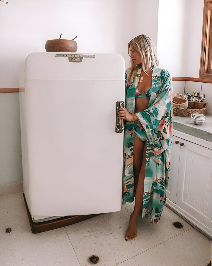 Femme blonde en bikini et kimono coloré devant un frigo vintage. Kimono fleuri de notre collection.