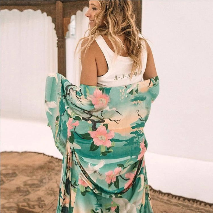 Femme portant un kimono fleuri turquoise et rose avec des motifs d'oiseaux. Kimono long et ample, idéal pour la détente. Vêtements de style japonais.