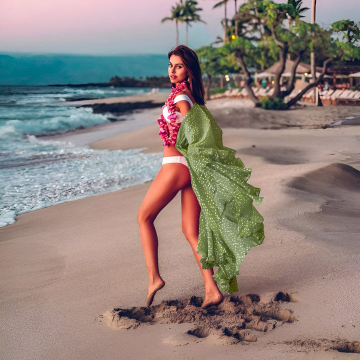 Femme sur la plage portant un kimono vert. Mer turquoise et ciel rose en arrière-plan. Vente de kimonos en ligne.
