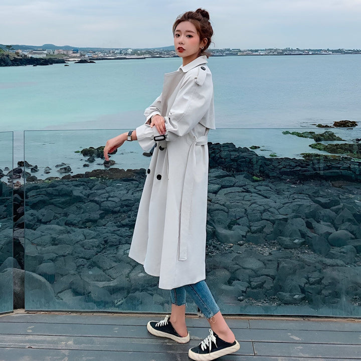 Femme portant un kimono long blanc avec une ceinture, posant près de l'océan. Notre collection de kimonos élégants et confortables. Trouvez le kimono parfait pour toutes les occasions.