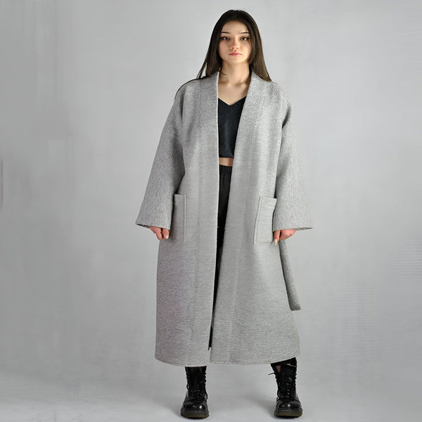 Femme portant un kimono long gris avec poches. Vêtement d'extérieur élégant et confortable. Découvrez notre collection de kimonos uniques.