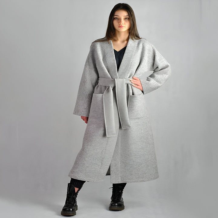 Femme portant un kimono gris long avec ceinture, poches et manches larges. Vêtements d'intérieur confortables et élégants. Kimonos à la vente en ligne.
