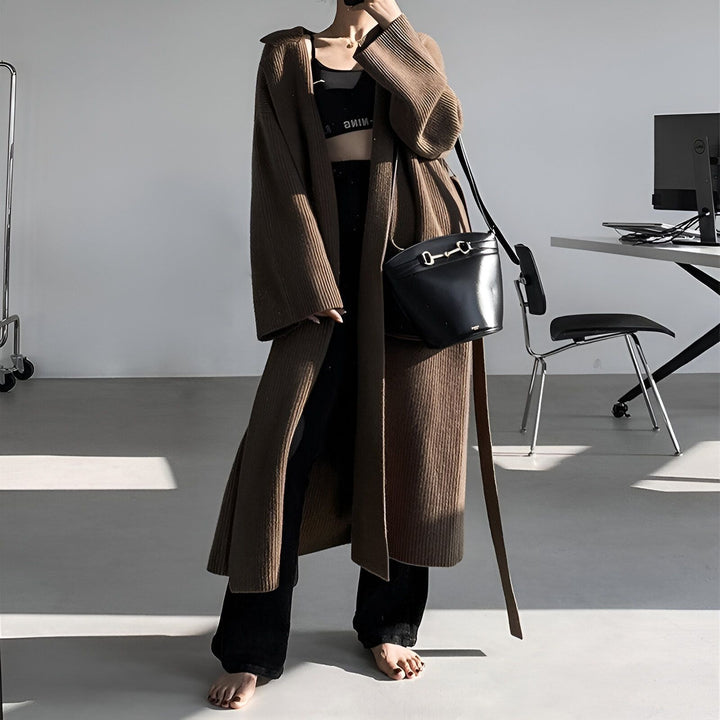 Femme portant un long kimono marron en tricot, un crop top noir, un pantalon noir et un sac à main noir. Vêtements de style kimono à vendre.