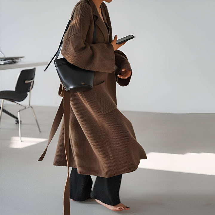 Femme portant un kimono marron en maille avec une ceinture et un sac noir, regardant son téléphone. Vêtements style kimono à la vente.