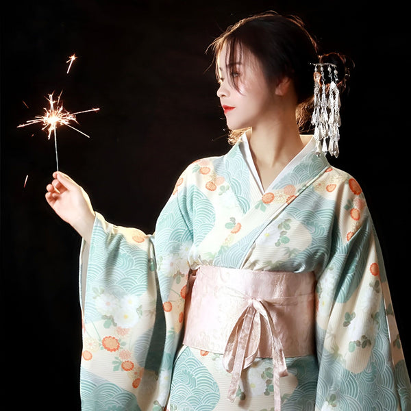 Femme en kimono traditionnel bleu et blanc avec motifs floraux, tenant un cierge magique. Vente de kimonos authentiques.