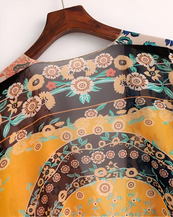 Kimono fleuri sur cintre en bois. Motifs floraux jaunes, noirs et marrons. Vêtement léger et tendance, idéal pour l'été. Découvrez notre collection de kimonos uniques.