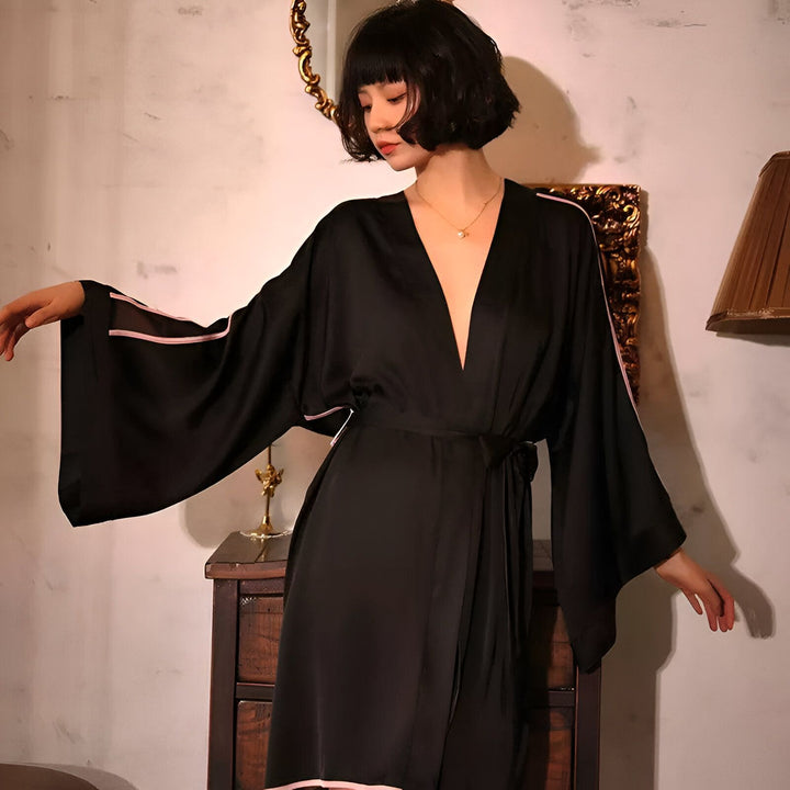 Femme portant un kimono noir en soie avec des détails roses. Vêtements de nuit élégants.