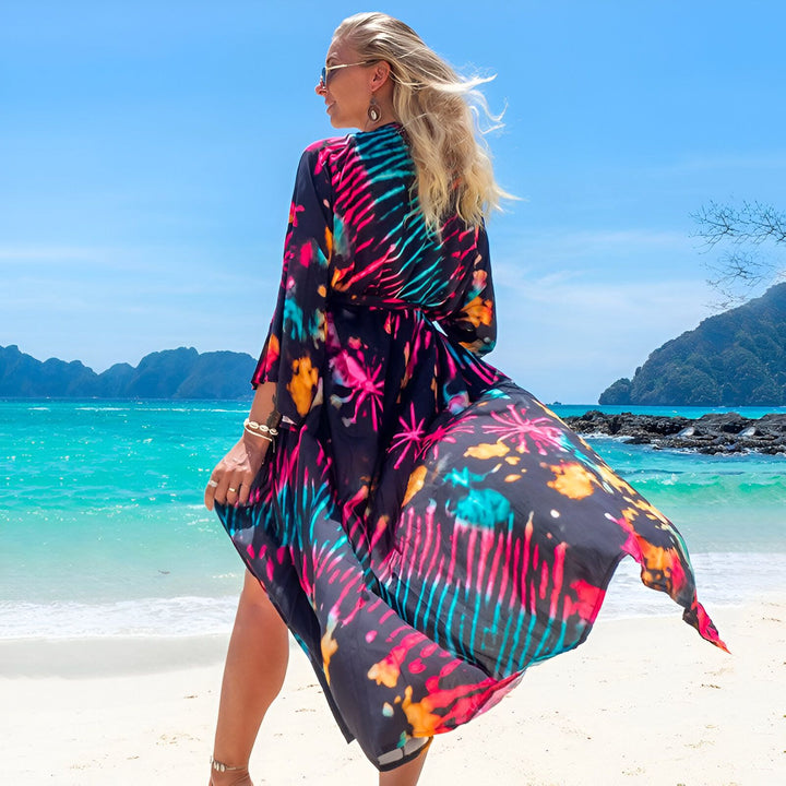 Femme blonde portant un kimono coloré sur une plage tropicale. Vente de kimonos pour femmes, motifs variés. Mode plage, vêtements d'été.