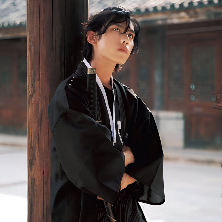 Homme portant un kimono noir traditionnel avec un katana. Découvrez notre collection de kimonos authentiques.