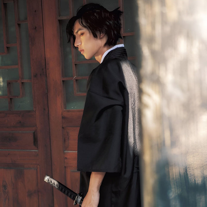 Homme en kimono noir traditionnel tenant un katana. Vêtements japonais authentiques. Découvrez notre collection de kimonos uniques.