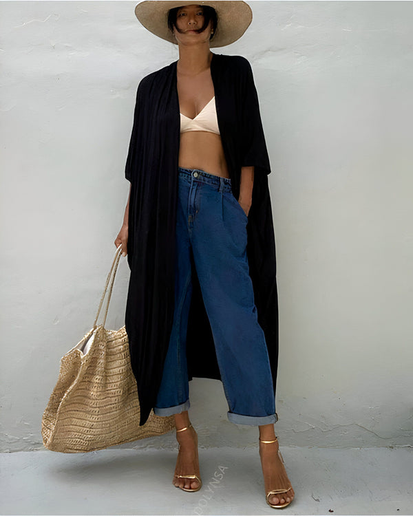Femme portant un kimono noir long, jean bleu, chapeau de paille et talons dorés. Sac en paille. Vêtements d'été, style décontracté. Kimonos élégants à vendre en ligne.