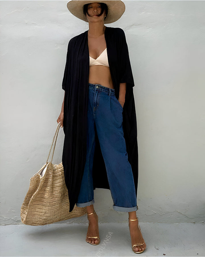 Femme portant un kimono noir long, jean bleu, chapeau de paille et talons dorés. Sac en paille. Vêtements d'été, style décontracté. Kimonos élégants à vendre en ligne.