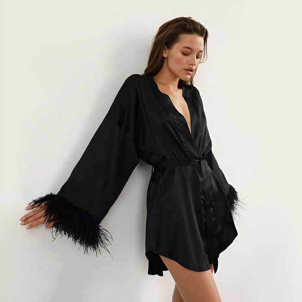 Femme portant un kimono noir en soie avec des plumes aux manches. Découvrez notre collection de kimonos luxueux en ligne.