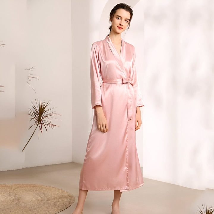 Femme portant un kimono rose en soie. Peignoir élégant avec ceinture, idéal comme vêtement d'intérieur confortable ou cadeau. Collection de kimonos de notre boutique en ligne.