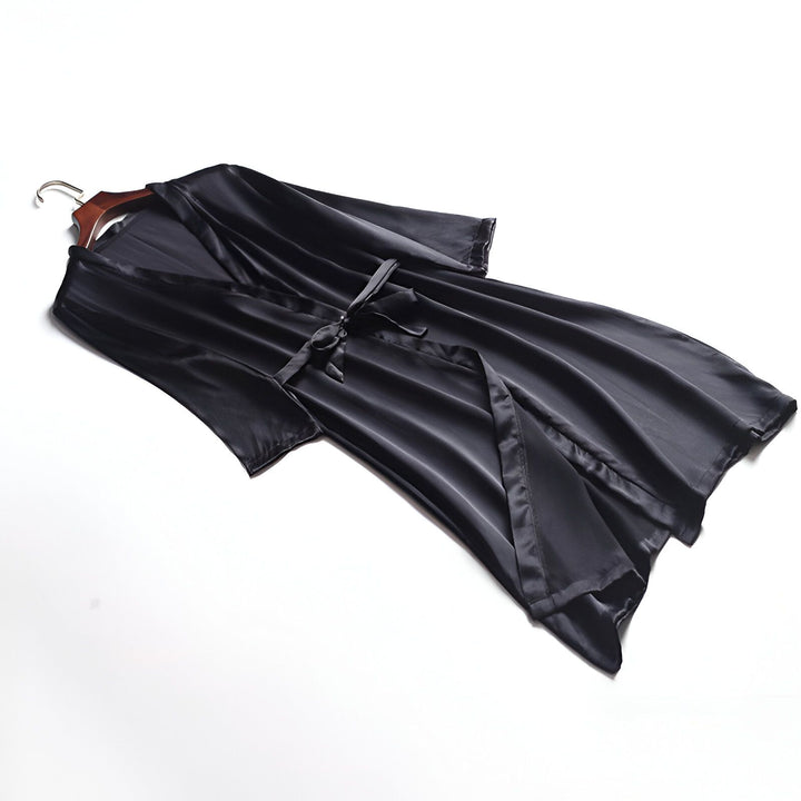 Kimono noir en satin sur un cintre. Élégant peignoir pour femme, idéal pour la détente. Découvrez notre collection de kimonos luxueux.