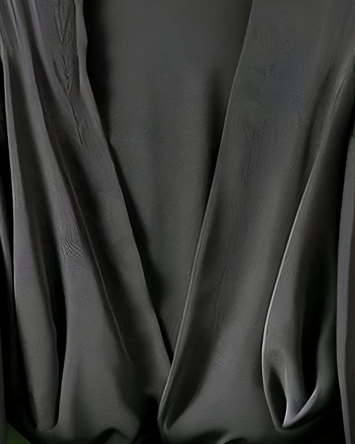 Gros plan sur le tissu noir et fluide d'un kimono élégant. Matière douce et drapée, idéale pour un style japonais moderne. Découvrez notre collection de kimonos.