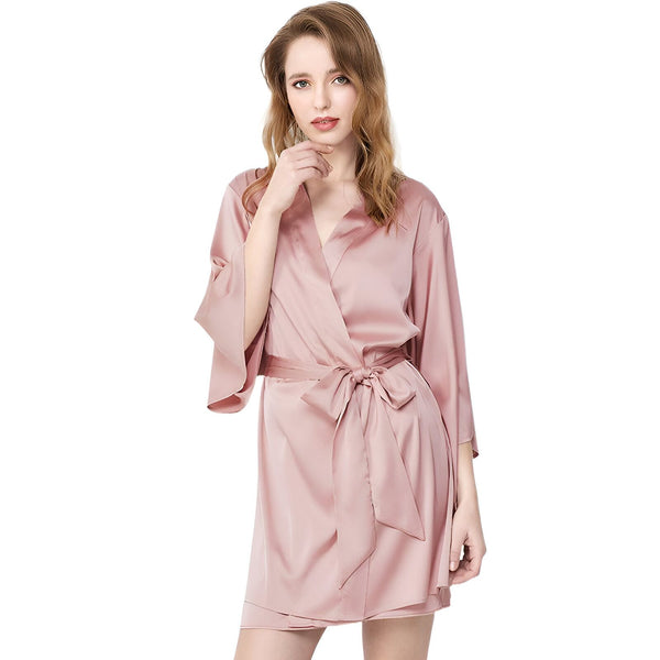 Femme portant un kimono rose en soie. Vêtement de détente élégant avec ceinture. Idéal comme peignoir ou robe de chambre. Collection de kimonos de luxe.