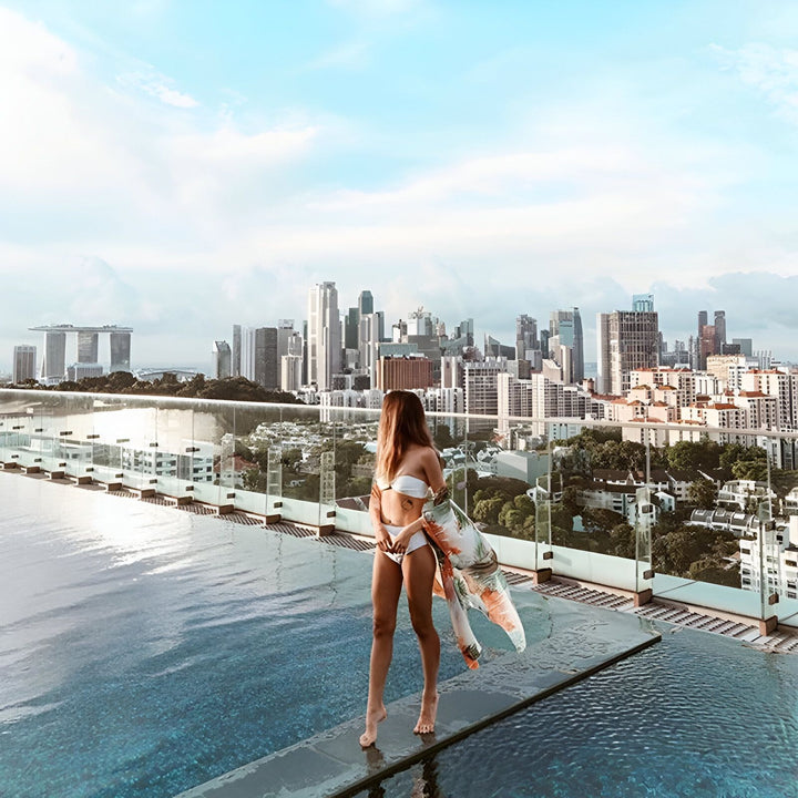 Femme au bord d'une piscine sur un toit-terrasse, portant un kimono fleuri. Vue panoramique sur la ville. Kimonos tendance pour toutes les occasions. Boutique en ligne de kimonos.