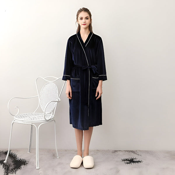 Femme portant un kimono bleu marine en velours avec ceinture. Peignoir kimono confortable et élégant, idéal pour la détente. Découvrez notre collection de kimonos.