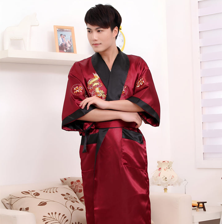 Homme asiatique portant un kimono bordeaux en soie avec des motifs de dragon brodés en or et des bordures noires. Kimonos de notre boutique.