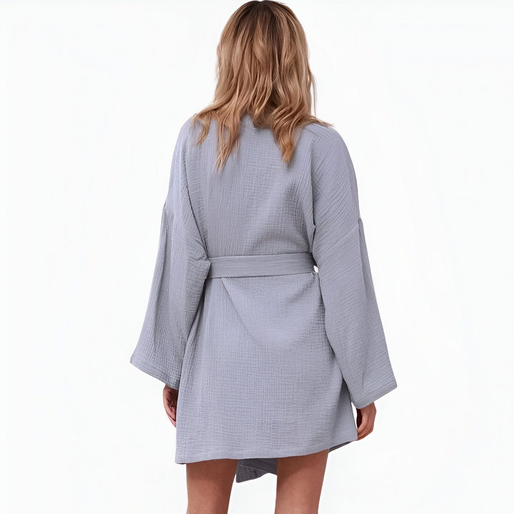 Dos d'une femme portant un kimono bleu clair. Kimono en coton gaufré avec ceinture. Idéal comme peignoir ou vêtement d'intérieur. Découvrez notre collection de kimonos élégants et confortables.