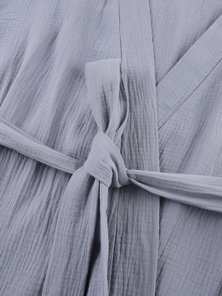 Détail d'un kimono gris clair avec ceinture nouée. Texture du tissu en lin froissé. Kimonos élégants et confortables pour toutes les occasions.