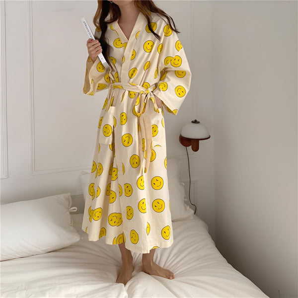 Kimono long crème avec motifs de visages souriants jaunes, vendu par [Nom de votre entreprise]. Parfait pour se détendre avec style.