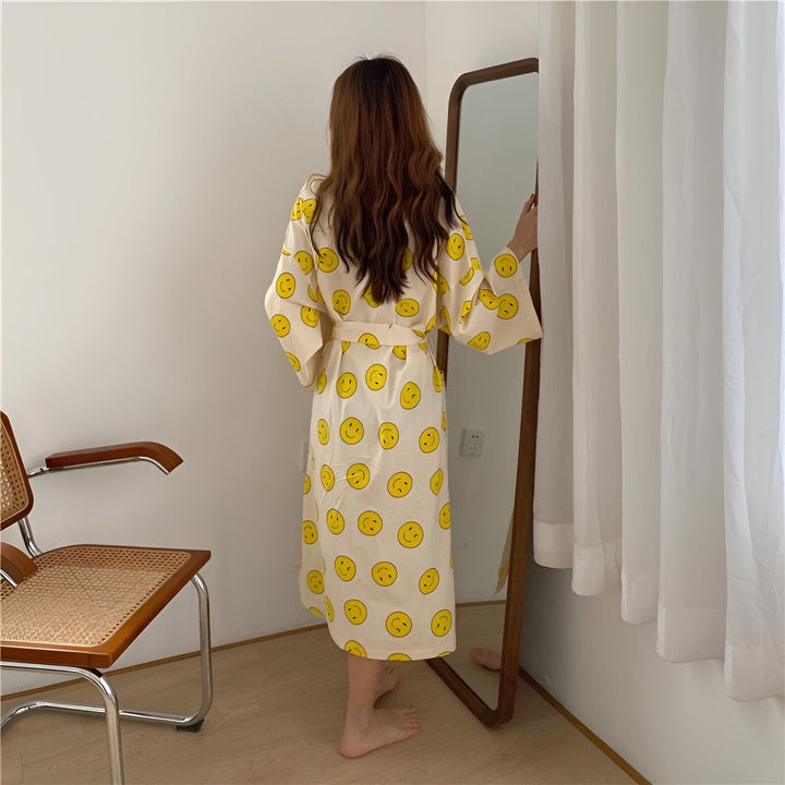 Femme vue de dos portant un kimono blanc à motifs de visages souriants jaunes, devant un miroir. Vente de kimonos en ligne.