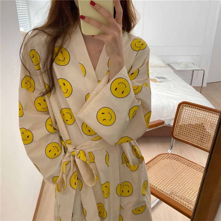 Femme portant un kimono à motifs de smileys jaunes. Kimono à motifs originaux, idéal pour se détendre avec style. Découvrez notre collection de kimonos.