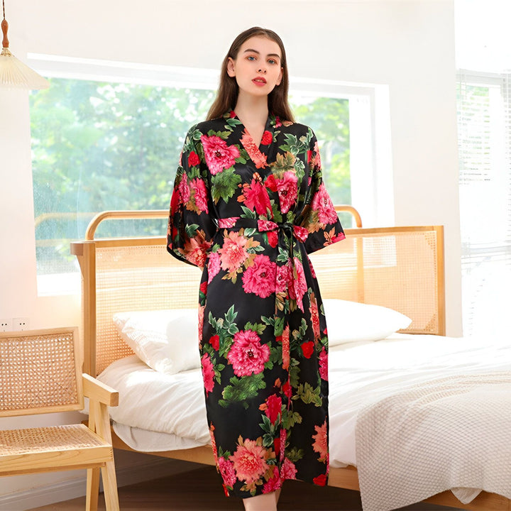 Femme portant un kimono fleuri noir et rose. Kimono élégant et confortable. Découvrez notre collection de kimonos en ligne.