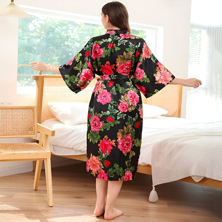 Femme portant un kimono fleuri noir et rose. Vêtement d'intérieur confortable avec ceinture. Kimonos élégants pour femmes disponibles en ligne.