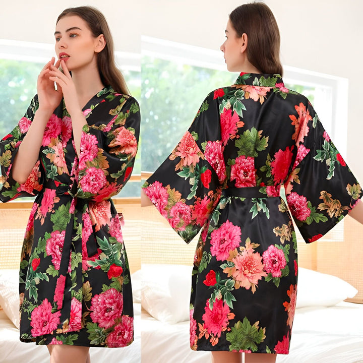 Femme portant un kimono fleuri noir et rose. Vue avant et arrière du peignoir en satin avec ceinture. Kimonos à motifs floraux disponibles à la vente.