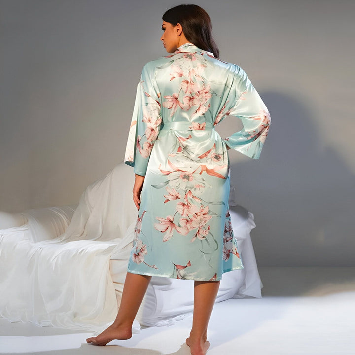 Femme portant un kimono turquoise à motifs floraux, vue de dos. Kimono en soie, élégant et confortable. Idéal pour se détendre à la maison ou comme vêtement de nuit raffiné.