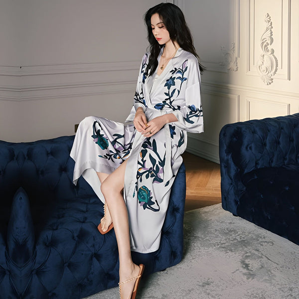 Femme assise sur un canapé en kimono gris fleuri. Kimonos élégants et confortables à vendre en ligne.